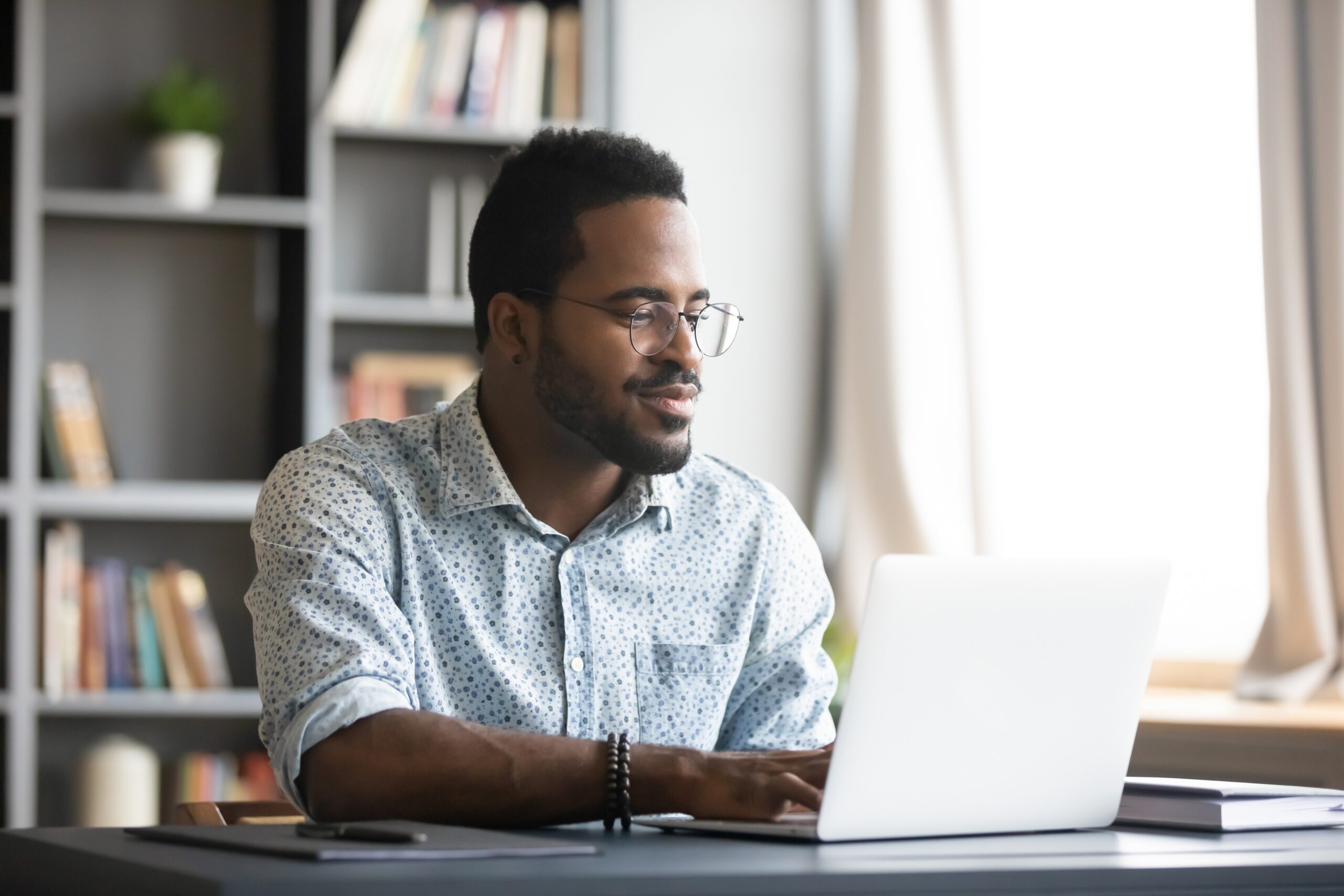 Satisfied,African,American,Man,Wearing,Glasses,Looking,At,Computer,Screen,